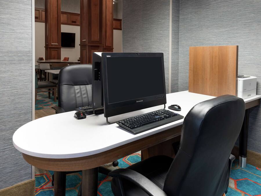 Une chambre d’hôtel équipée d’un bureau rond, d’un ordinateur, d’un clavier, d’une souris et d’une chaise.