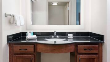 A bathroom with a black countertop, a white sink, and wooden cabinets.