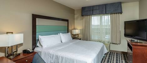 A hotel room with a bed, a desk, a television, and a ceiling fan.