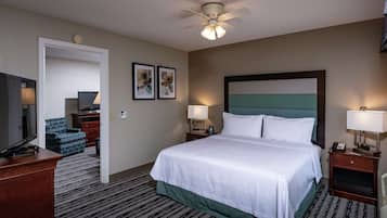 A hotel room with a bed, a desk, a television, a chair, and a ceiling fan.