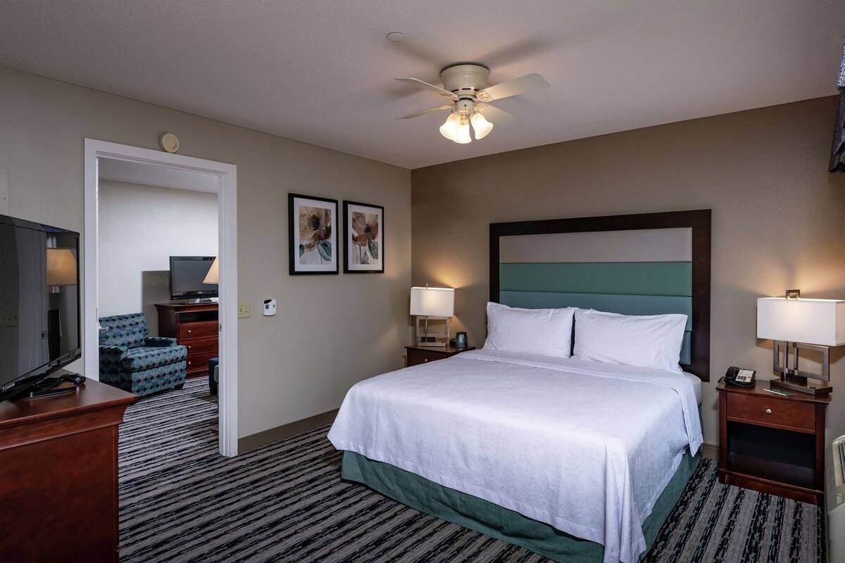 A hotel room with a bed, a television, a desk, and a chair.