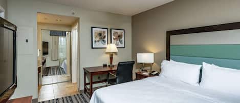 A hotel room with a bed, desk, chair, and a ceiling fan.