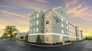Un hotel de varios pisos con fachada verde y beige, múltiples ventanas y un letrero que indica que es un Homewood Suites Hilton.