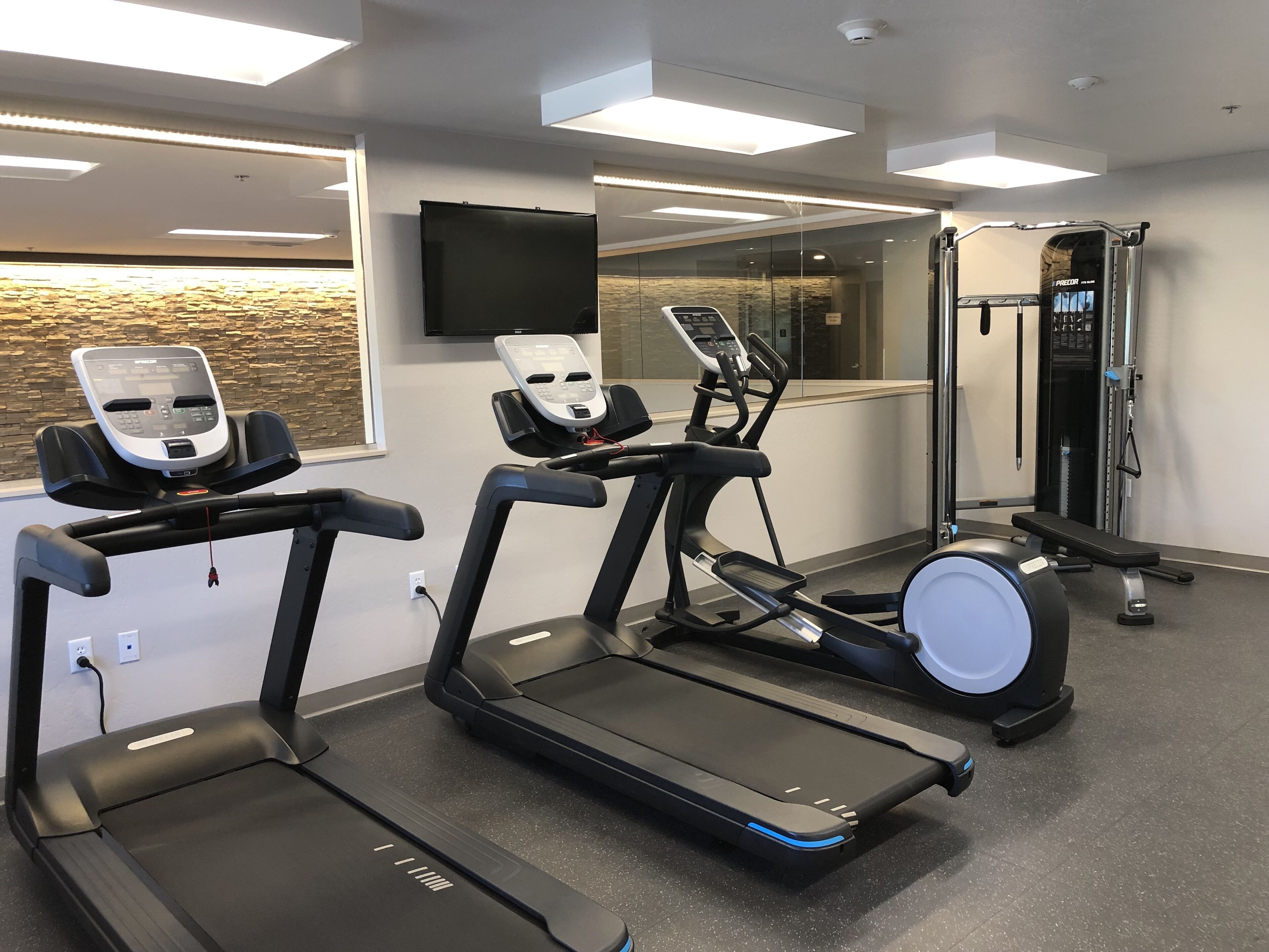 Academia com esteiras, bicicleta ergométrica e aparelho de musculação.