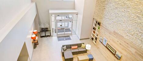 Un hall d’entrée spacieux, avec un canapé moderne, une table basse, un tapis et un mur orné de tableaux encadrés.