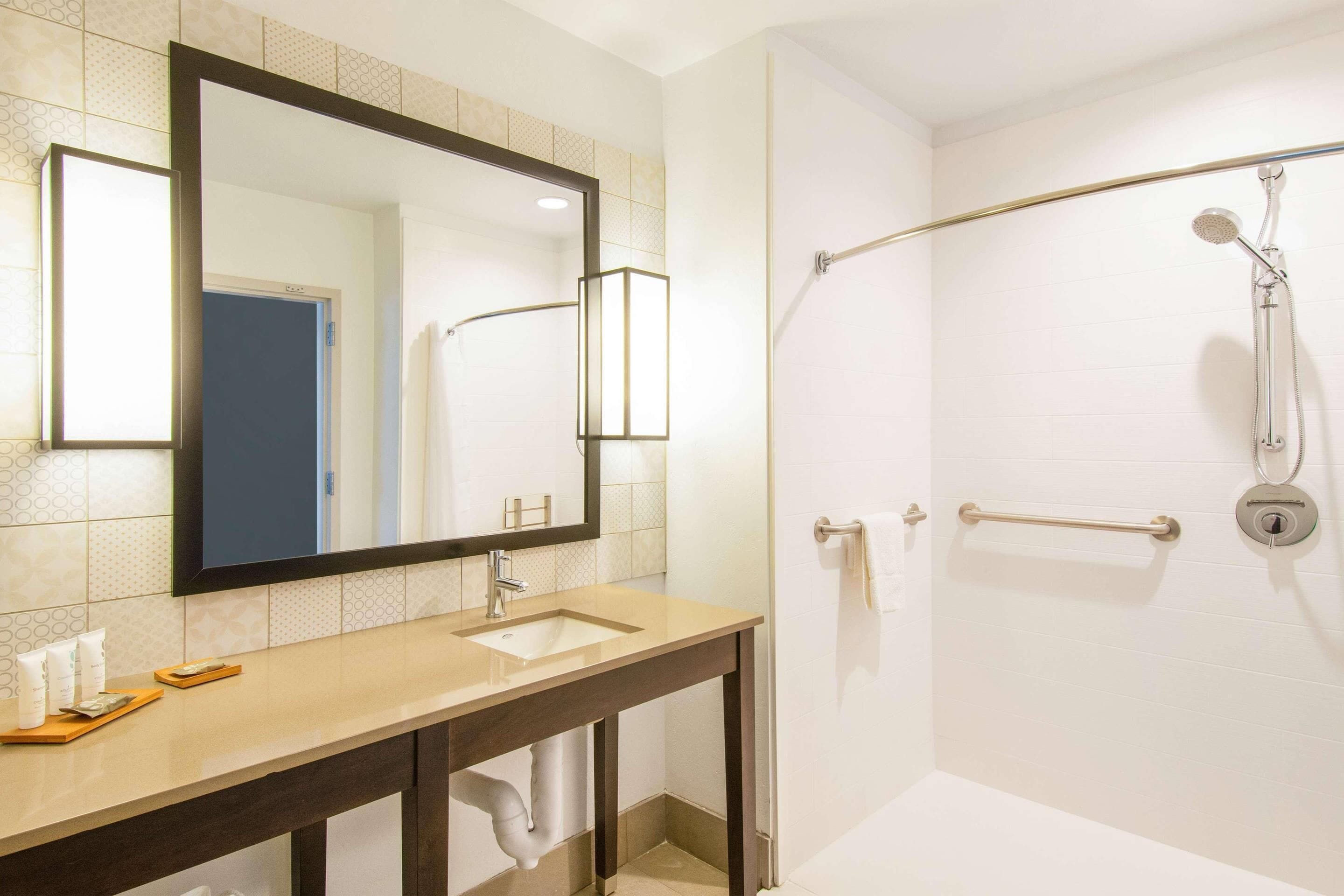 A bathroom with a sink, mirror, and shower.