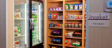A refrigerated display case and shelves stocked with snacks and beverages.