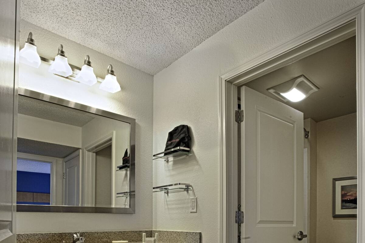 A bathroom with a wooden vanity, a mirror, a sink, and a toilet.