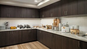 A modern kitchen with dark wood cabinets, a white countertop, and various food items and appliances. - Residence Inn Atlantic City Airport Egg Harbor Township (Egg Harbor Township)