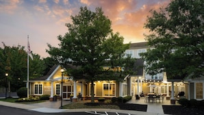 A hotel with a well-lit entrance, outdoor seating area, and a flagpole. - Residence Inn Atlantic City Airport Egg Harbor Township (Egg Harbor Township)