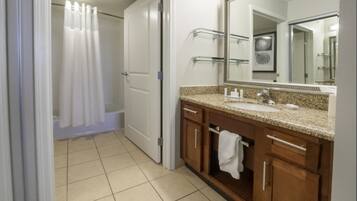 A bathroom with a shower, a sink, and a mirror.