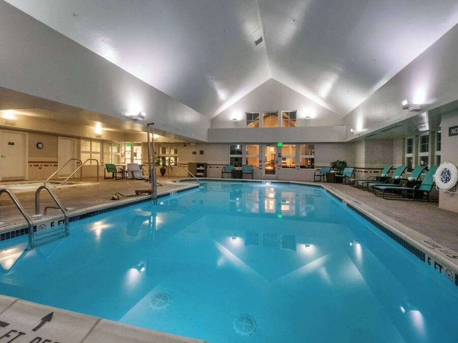 Una piscina interior con demarcaciones claras para carriles, una silla de salvavidas y un cartel de 'No Diving'.