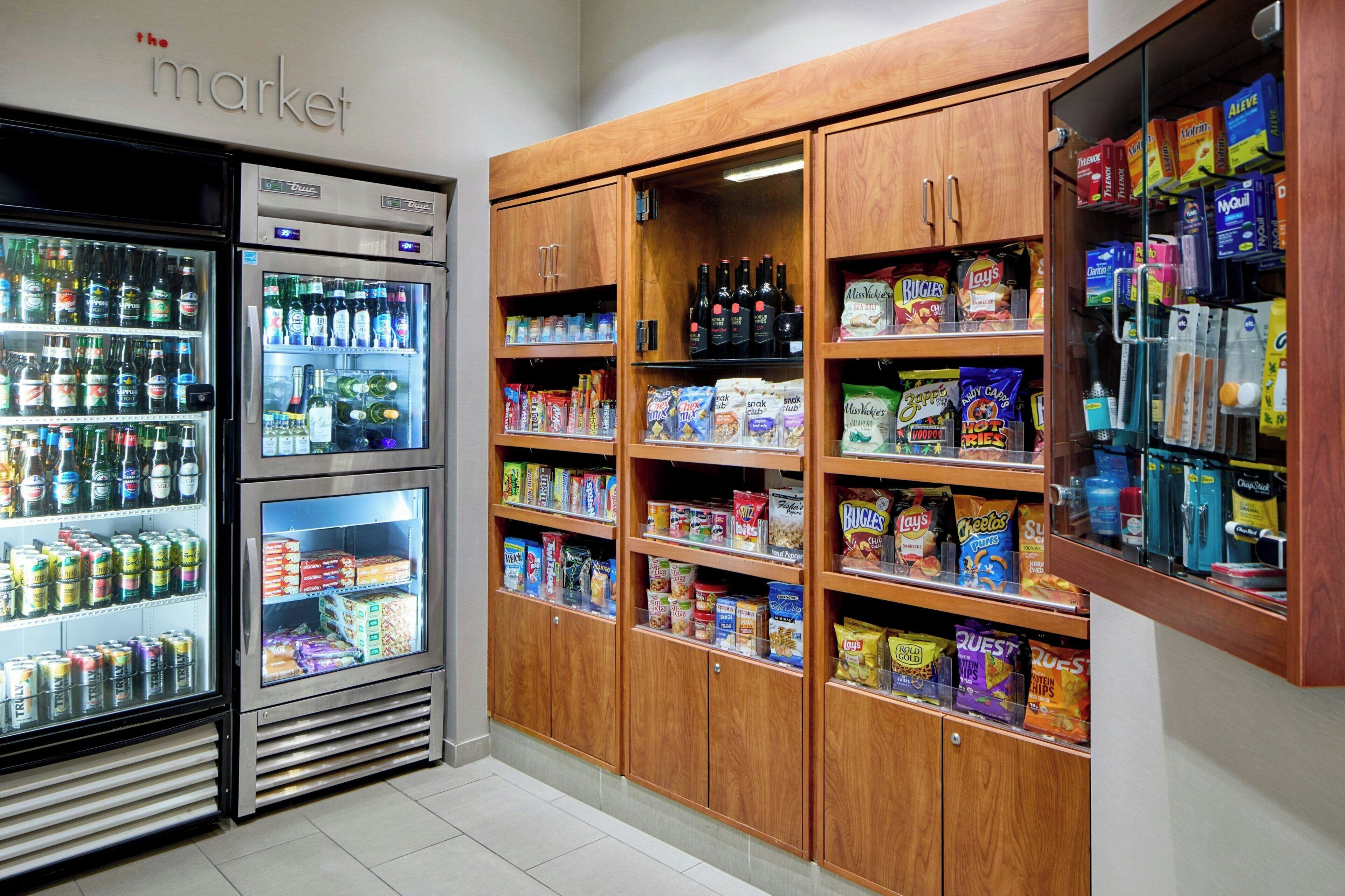 Una sección refrigerada con diversas bebidas y aperitivos, armarios de madera con más provisiones y bebidas, y un letrero que dice 'market'.