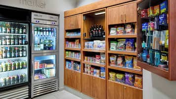 Una sección refrigerada con diversas bebidas y aperitivos, armarios de madera con más provisiones y bebidas, y un letrero que dice 'market'.