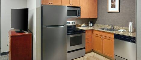 A modern kitchen with stainless steel appliances, wooden cabinets, and a granite countertop.