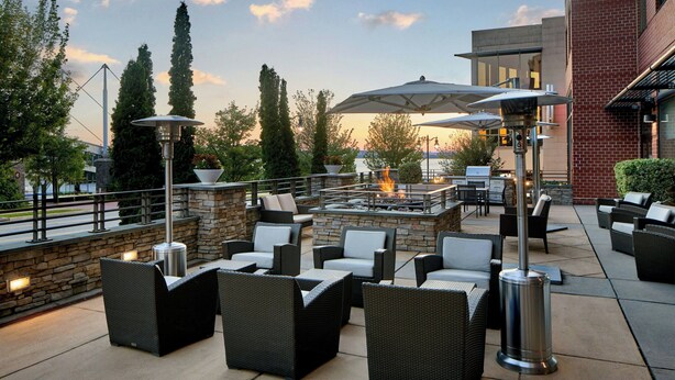 An outdoor patio with wicker furniture, umbrellas, and a fire feature. - Residence Inn National Harbor Washington, DC Area (Oxon Hill)