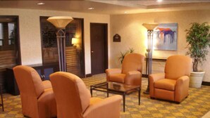 A lobby with four orange armchairs, a glass coffee table, and a floor lamp. There is a painting on the wall and a potted plant. - Holiday Inn Express & Suites Oro Valley-Tucson North by IHG (Oro Valley)