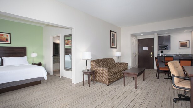 A hotel room with a bed, a sofa, a small table, a chair, and a kitchenette area. - Holiday Inn Express & Suites Oro Valley-Tucson North by IHG (Oro Valley)