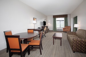 Een hotelkamer met een eettafel, stoelen, een bank, een televisie en een bureau.