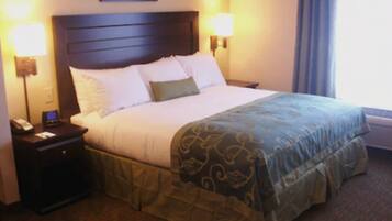 Una habitación de hotel con una cama grande, dos mesitas de noche y una lámpara fijada a la pared.