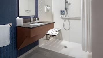 Une salle de bain moderne avec un grand miroir, un lavabo, une douche et un porte-serviettes.