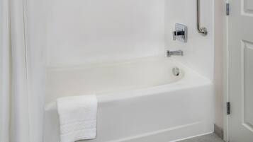 Uma casa de banho moderna com uma banheira branca, uma toalha e um painel de controlo de chuveiro.