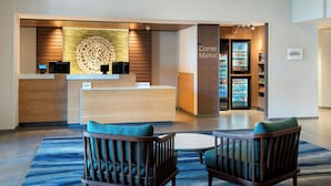 A hotel lobby with a reception desk, a corner market, and seating area. - Fairfield Inn & Suites by Marriott Rome (Rome)