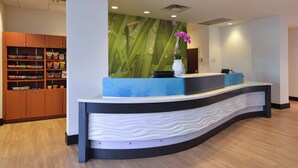A reception desk with a blue and white design, a wooden cabinet with snacks, and a wall with a green leaf pattern. - Springhill Suites by Marriott Oklahoma City Airport (Oklahoma City)