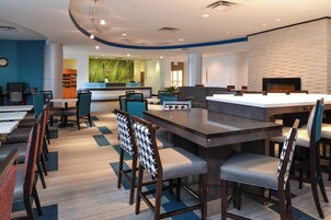 Un espacio lounge moderno con mesa de billar, bar y asientos.