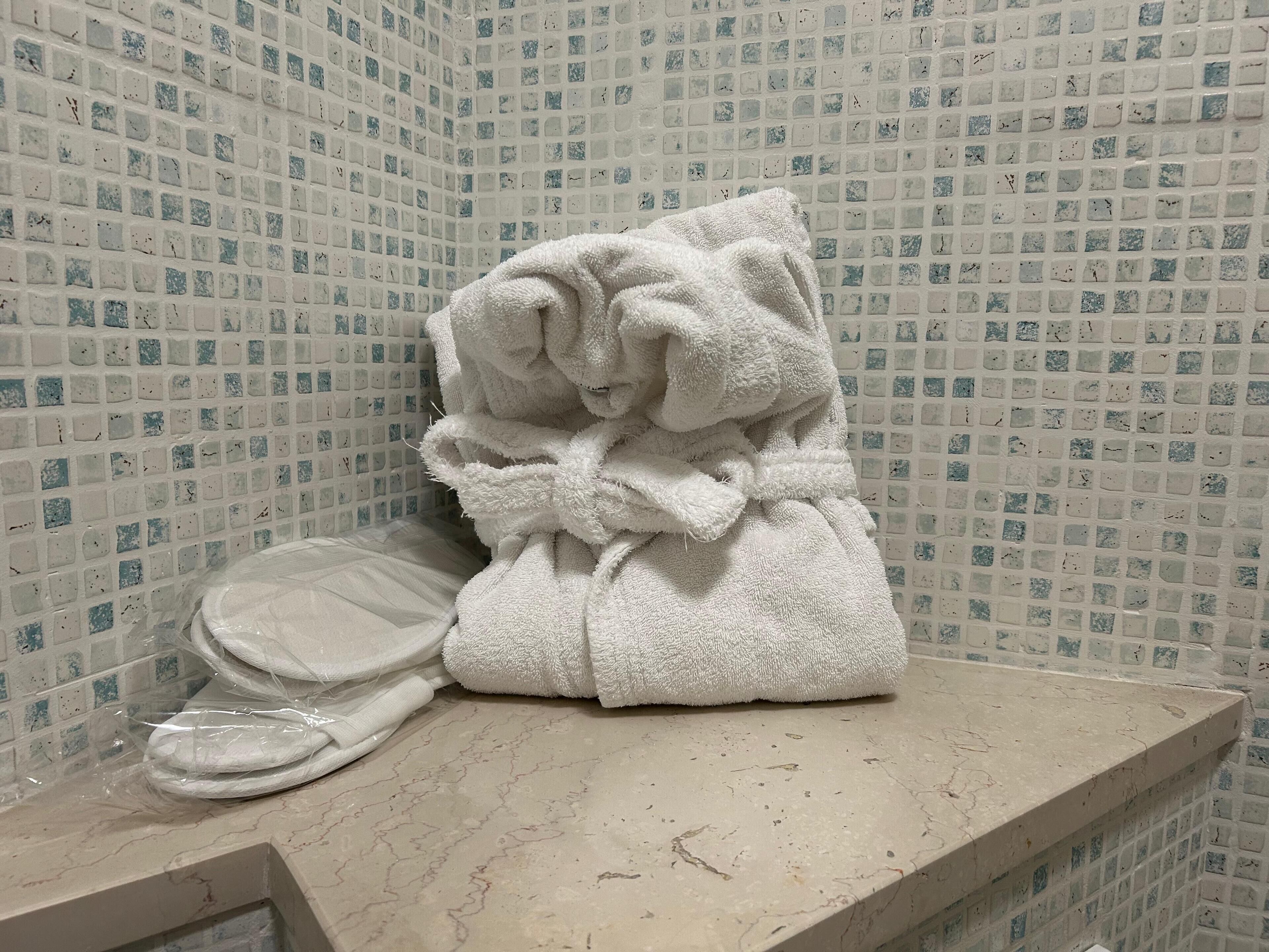 A bathroom with a tiled wall and a marble countertop.