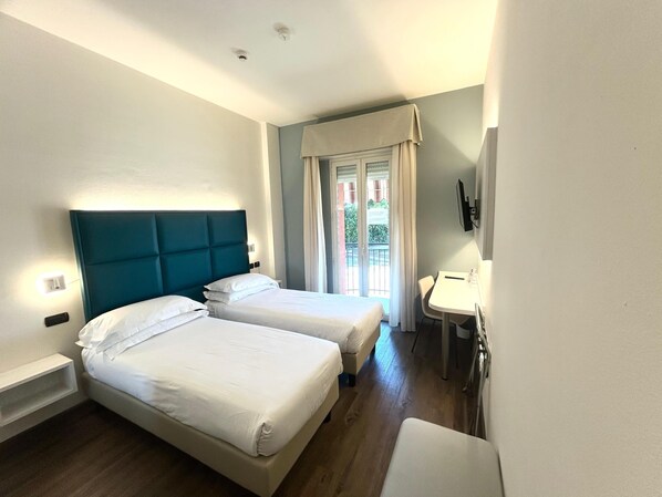 A hotel room with two beds, a small desk, a TV, and a balcony with curtains. - Best Western Cesena Hotel (Cesena)