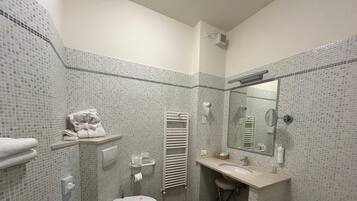 Un bagno con il water, un lavandino, un portascopevoli e uno specchio.