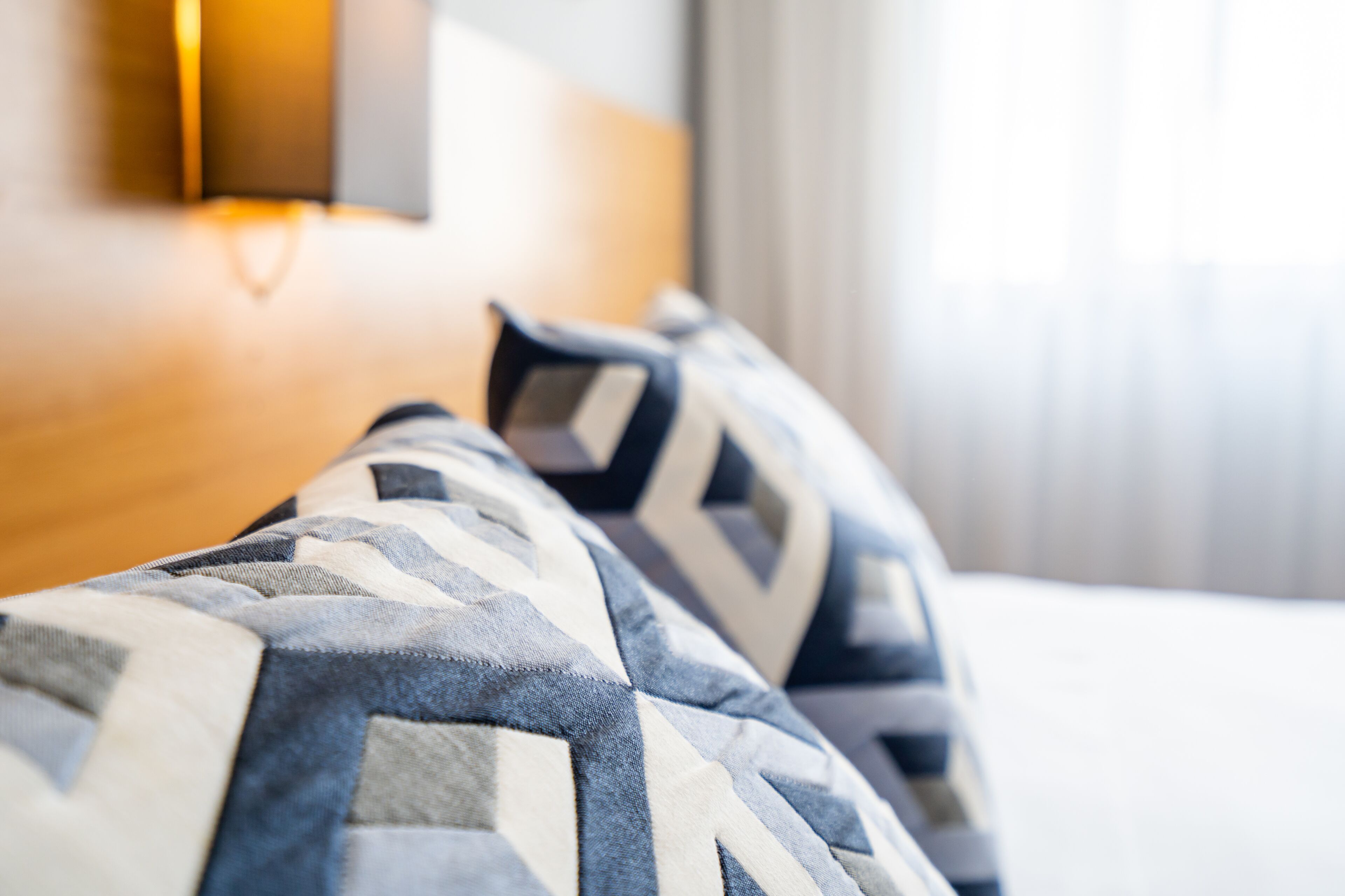 A close-up of a bed with patterned pillows and a wooden headboard.