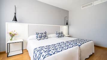 Ein modernes Hotelzimmer mit einem großen Bett, Nachttischen, einer Blumenvase und einem Deckenventilator.