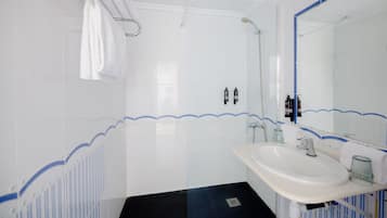 A bathroom with a white sink, a mirror, and a shower.