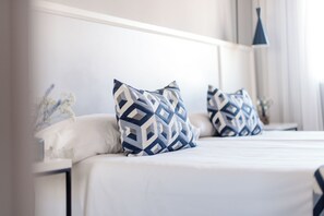 Una cama bien hecha con almohadas estampadas y un cabecero moderno y limpio.