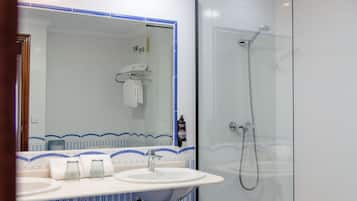 Un baño con un espejo grande, un lavamanos y una ducha.