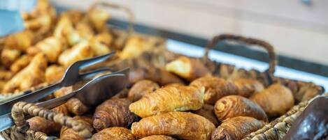 A basket of assorted pastries, including croissants and other baked goods, on a countertop.