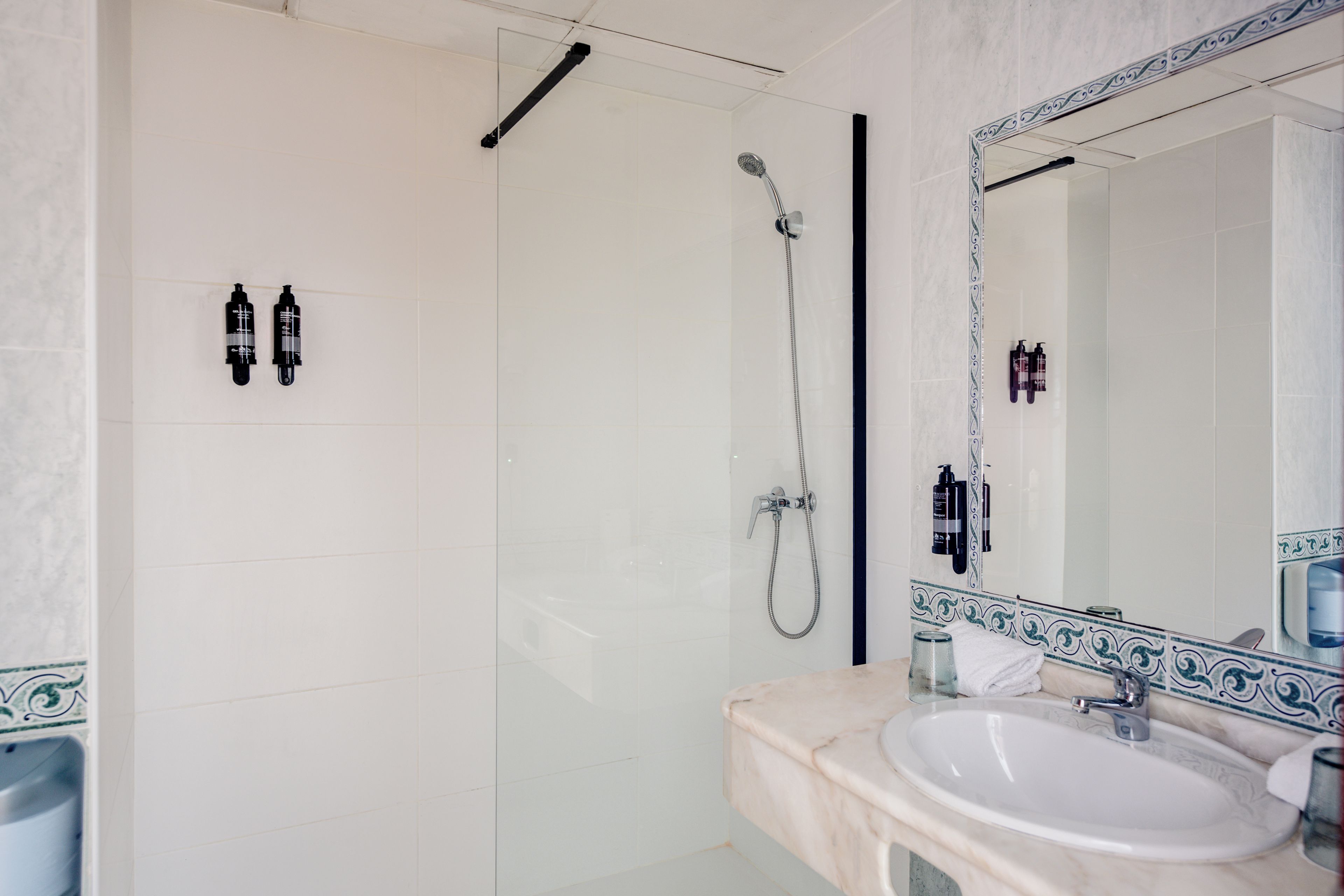 Ein Badezimmer mit Dusche, Waschbecken und Spiegel.