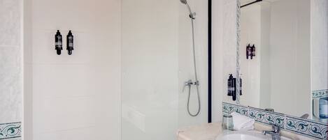 Un baño con ducha, lavamanos y espejo.