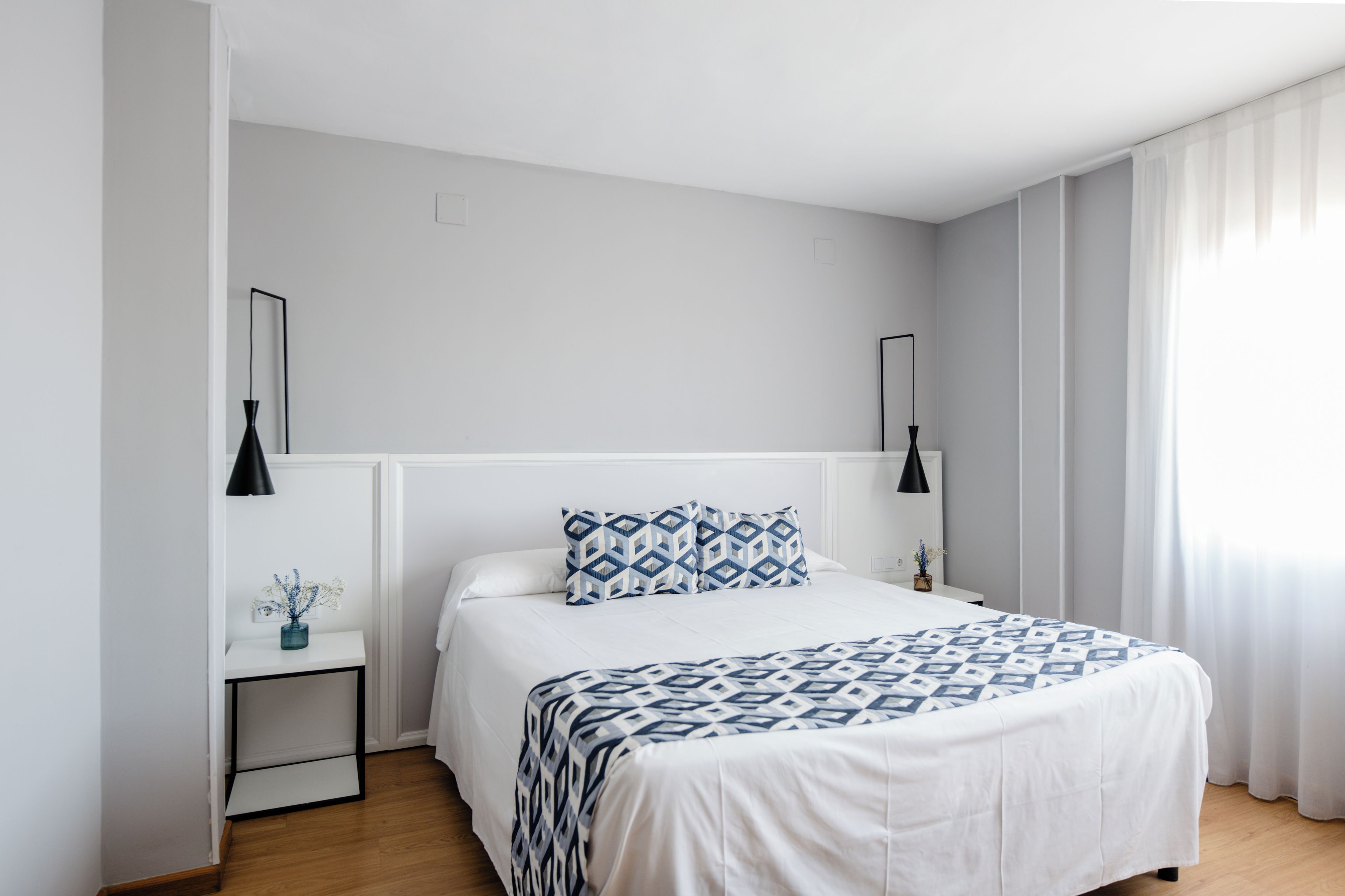 Un dormitorio moderno con cama, mesitas de noche y una mesilla.