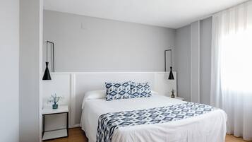Un dormitorio moderno con cama, mesitas de noche y una mesilla.