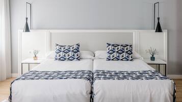 Een tweepersoonsbed met een sprei met een geometrisch patroon, twee bijpassende kussens en een wit hoofdbord.