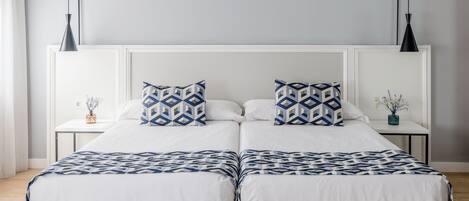 Una cama doble con colcha de diseño geométrico, dos almohadas a juego y un cabecero blanco.