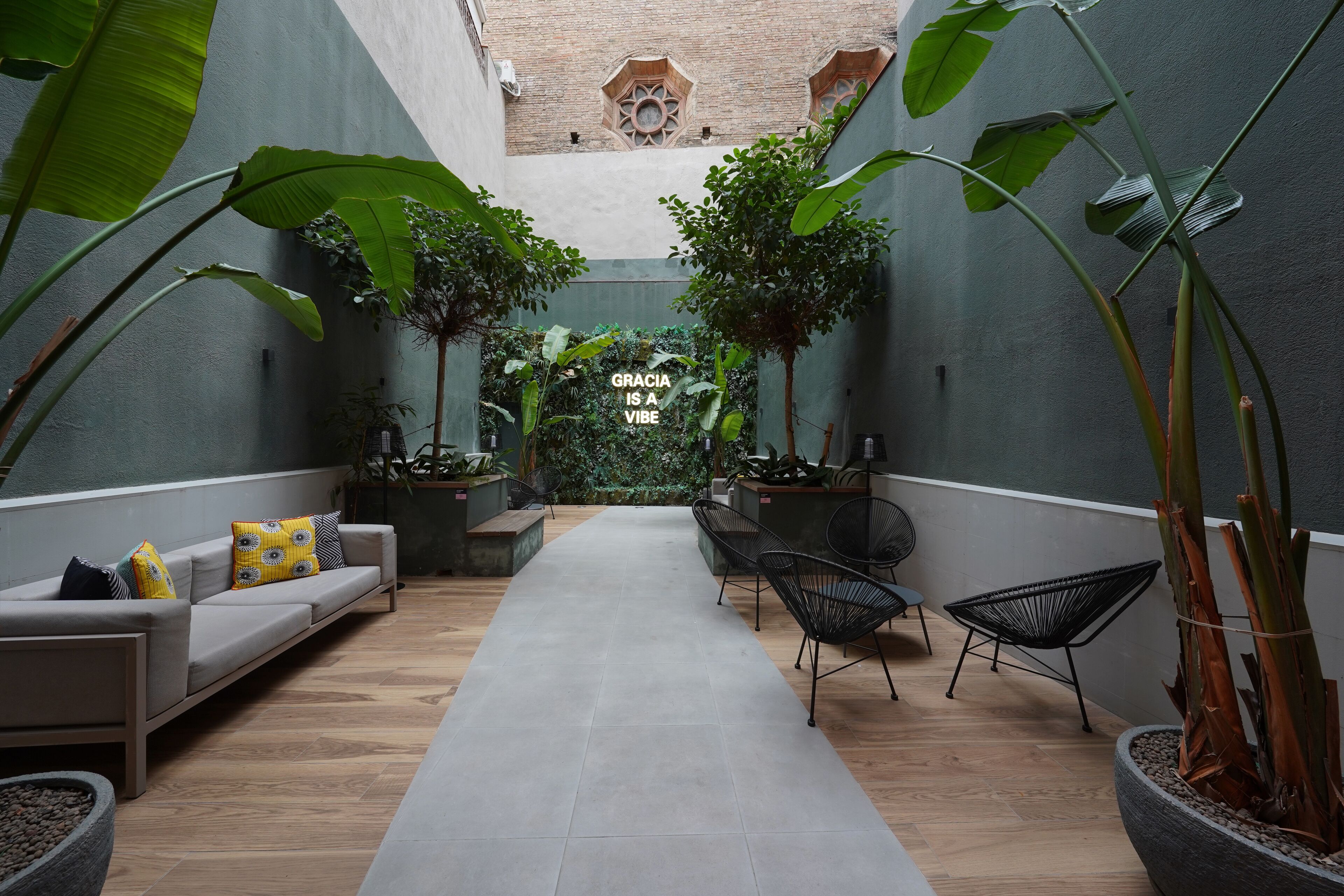 Een modern interieur met een centrale doorgang, zithoeken en grote groene planten.