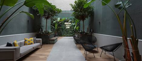 Een modern interieur met een centrale doorgang, zithoeken en grote groene planten.