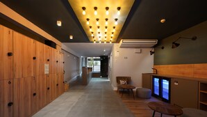 A hotel lobby with wooden lockers, a reception desk, a seating area, and a digital display. - Numa Barcelona Brio (Barcelona)
