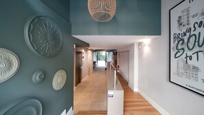 A hallway with a wooden floor, a staircase with a white railing, and decorative wall panels. - Numa Barcelona Brio (Barcelona)