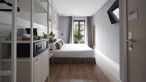 A bedroom with a bed, a wardrobe, a desk with a lamp, and a window with curtains. - Numa Barcelona Brio (Barcelona)
