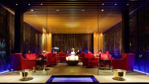 Un salón moderno con asientos rojos, un hogar central y una fuente iluminada en azul.